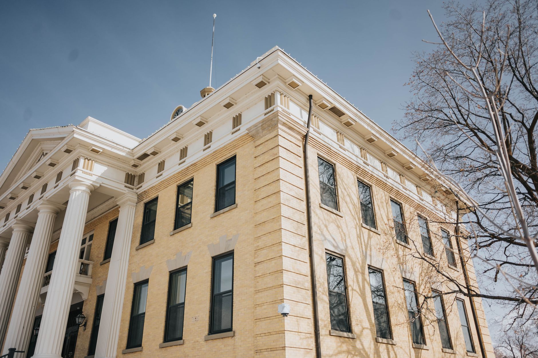 Low angle view of the historic Box Elder County Courthouse with columns and blue sky, Brigham City, Utah, illustrating What Is the Ada County Courthouse, and What Are Its Murals