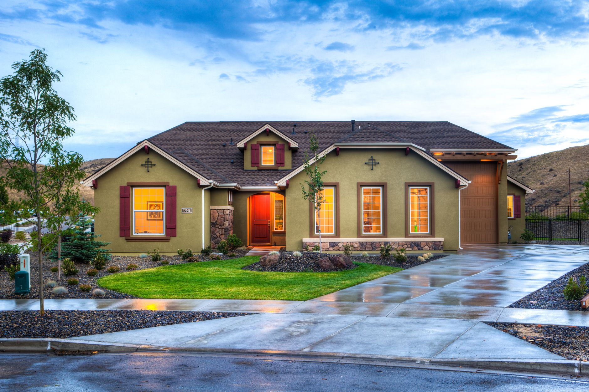 Beautifully illuminated modern home exterior with a lush lawn and wet driveway in Boise, Idaho, illustrating How Boise's Geothermal System Works, and What It Heats