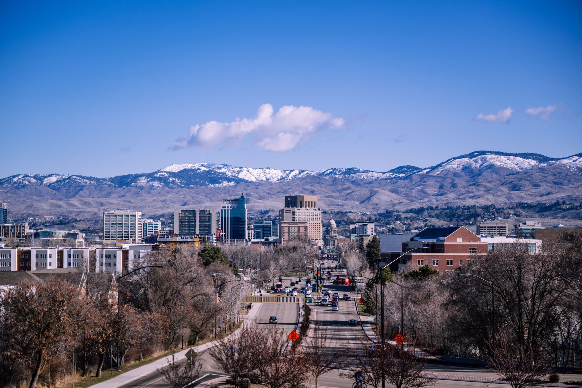 A stunning view of downtown Boise, Idaho, featuring mountains and clear blue skies, illustrating How Boise's Geothermal System Works, and What It Heats