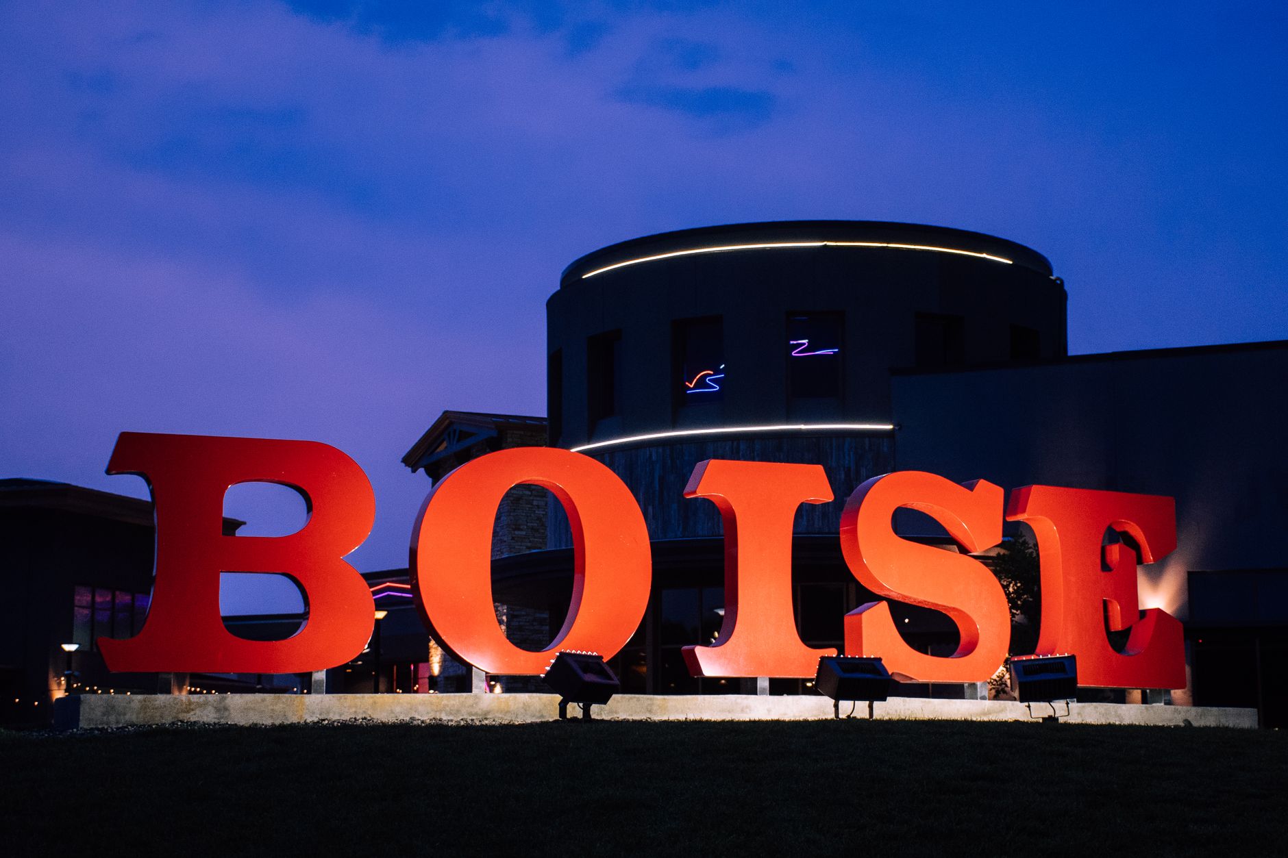 Large red 'Boise' sign against a modern building at twilight, illustrating What Is the Difference Between Boise, Meridian and Eagle