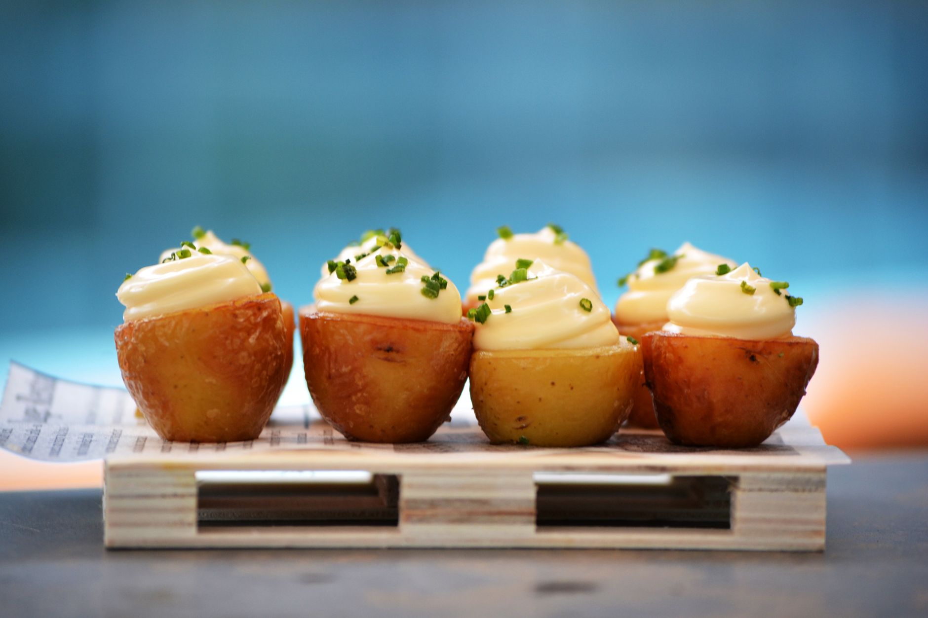 Delicious gourmet potato appetizers topped with cream and fresh chives on a wooden platter, illustrating What Is an Ice Cream Potato, and Is It a Real Thing
