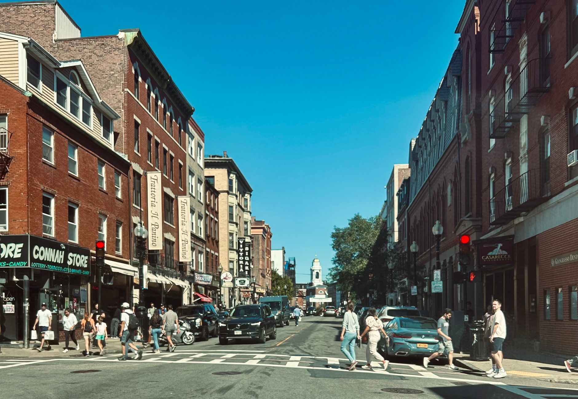 Vibrant street view of Hanover Street in Boston's North End with pedestrians and red brick buildings, illustrating What Is Boise's North End, and Why Does It Look Like That