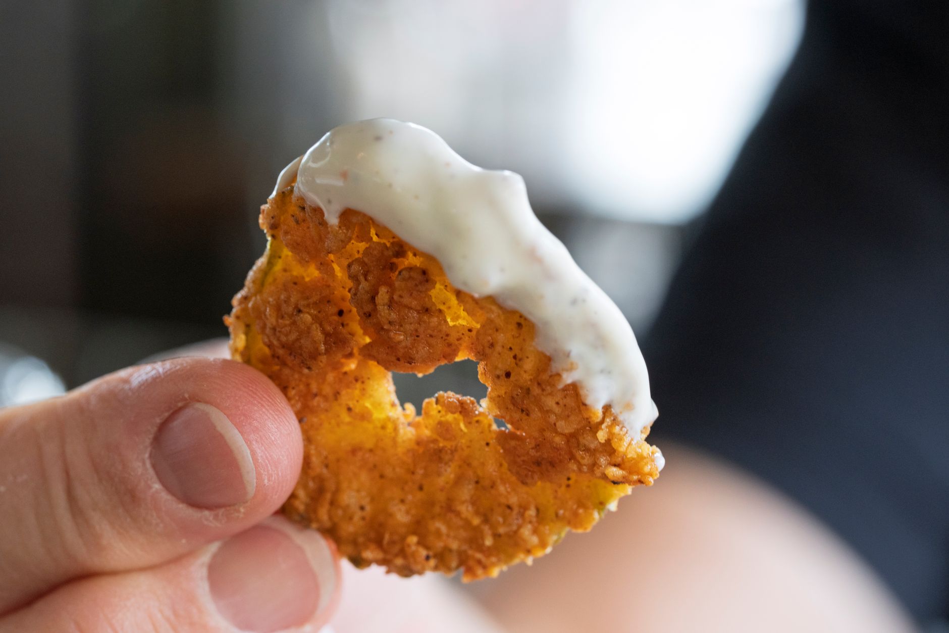 Close up shot of a crispy fried onion ring with creamy dipping sauce. Perfect for food lovers