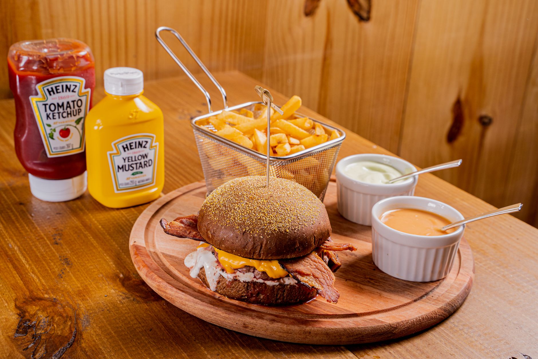 Delicious bacon cheeseburger served with crispy fries, ketchup, mustard, and sauces